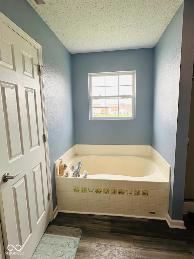 1071 Hazelwood Dr, Greenwood, IN 46143 - full bath featuring a bath, wood finished floors, a textured wall, and a textured ceiling