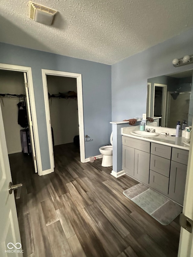 1071 Hazelwood Dr, Greenwood, IN 46143 - full bath with vanity, a textured ceiling, toilet, visible vents, and wood finished floors