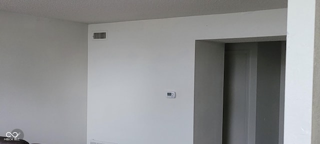 interior space featuring elevator, a textured ceiling, and visible vents