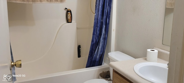 bathroom with toilet, vanity, a textured wall, and shower / bath combo with shower curtain