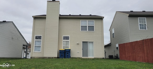rear view of property featuring a chimney, fence, and a yard
