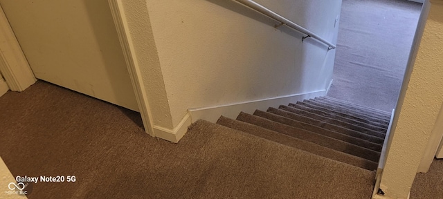 staircase with carpet and a textured wall