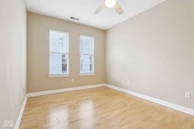 spare room featuring light wood-style flooring, baseboards, ceiling fan, and visible vents