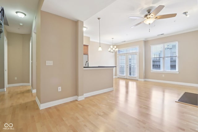 unfurnished living room featuring baseboards, visible vents, light wood-style flooring, and ceiling fan with notable chandelier