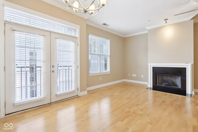 unfurnished living room featuring ornamental molding, wood finished floors, french doors, and a notable chandelier