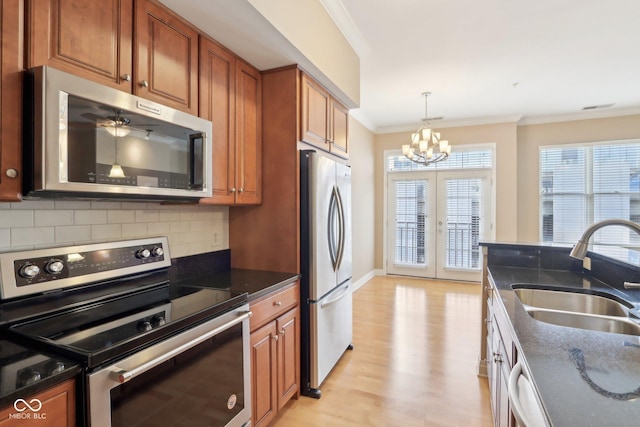 kitchen featuring ornamental molding, stainless steel appliances, a sink, a notable chandelier, and brown cabinetry