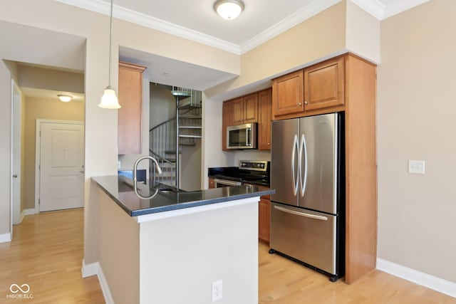kitchen featuring a sink, a peninsula, stainless steel appliances, dark countertops, and ornamental molding