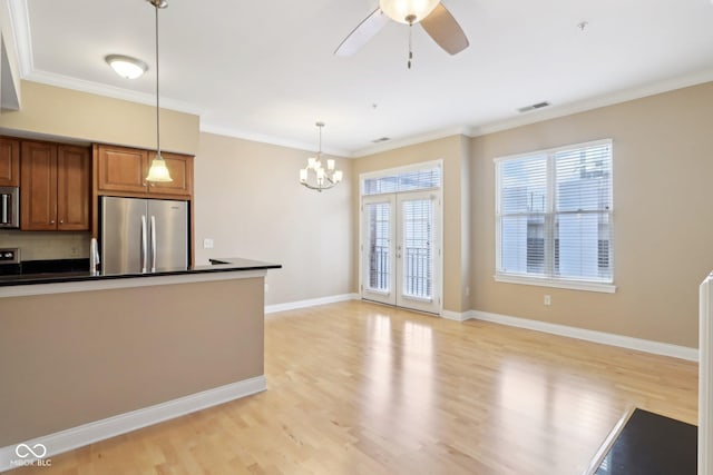 kitchen featuring brown cabinets, dark countertops, stainless steel appliances, ceiling fan with notable chandelier, and visible vents