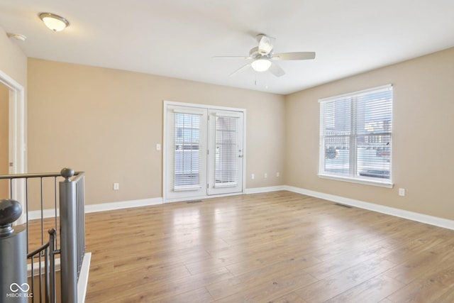spare room featuring wood finished floors, visible vents, baseboards, and ceiling fan