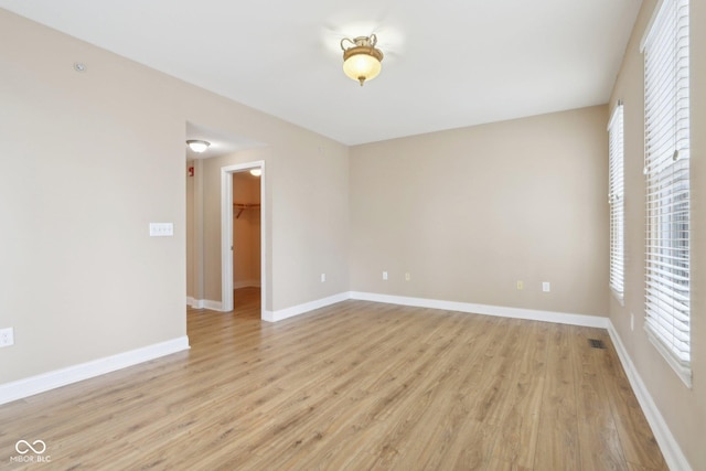 empty room with baseboards, light wood-type flooring, and visible vents