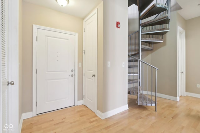 foyer featuring baseboards, stairway, and wood finished floors