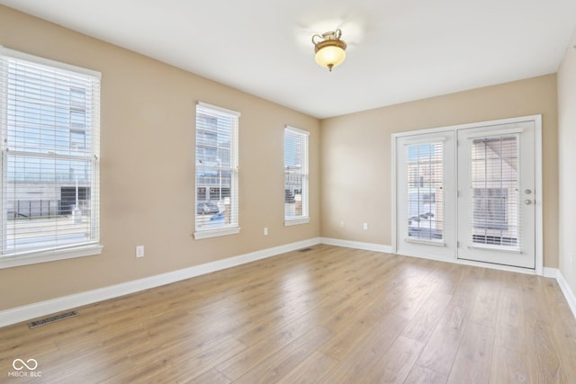 spare room with light wood-type flooring, baseboards, and visible vents
