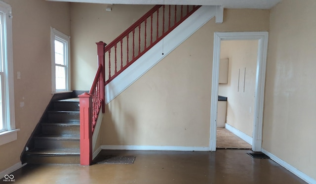 staircase with baseboards and concrete flooring