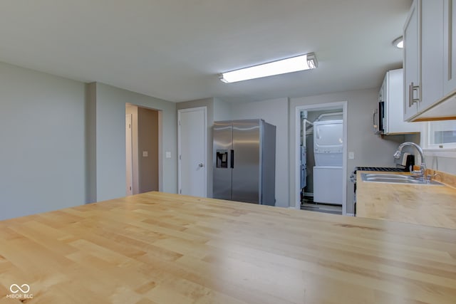 2205 Lafayette Rd, Crawfordsville, IN 47933 - kitchen with white cabinets, a sink, butcher block countertops, stainless steel fridge with ice dispenser, and stacked washer / drying machine