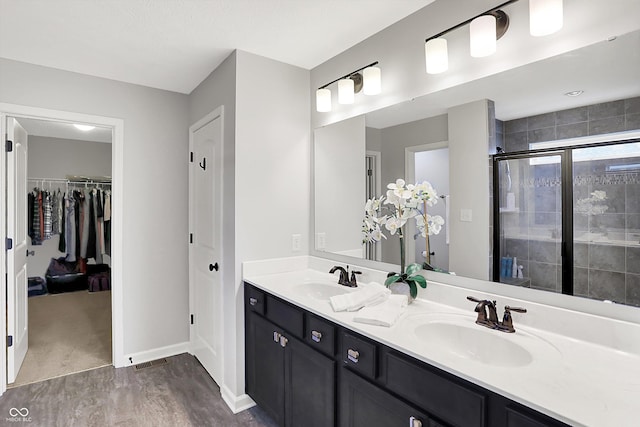16491 Wheatley Ct, Fishers, IN 46040 - full bath featuring wood finished floors, double vanity, a shower stall, a walk in closet, and baseboards