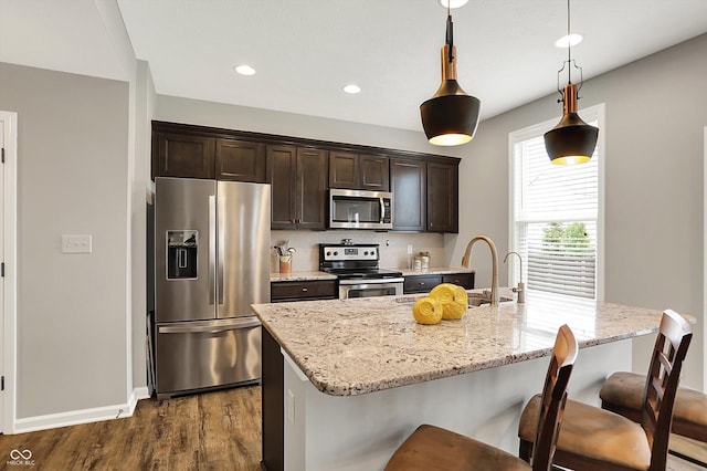 16491 Wheatley Ct, Fishers, IN 46040 - kitchen with appliances with stainless steel finishes, dark wood-style floors, dark brown cabinets, a kitchen bar, and a kitchen island with sink