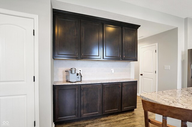 16491 Wheatley Ct, Fishers, IN 46040 - kitchen featuring wood finished floors, tasteful backsplash, light stone counters, and dark brown cabinets