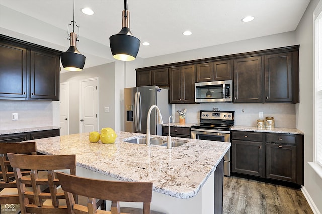 16491 Wheatley Ct, Fishers, IN 46040 - kitchen with appliances with stainless steel finishes, a sink, wood finished floors, dark brown cabinets, and a kitchen breakfast bar