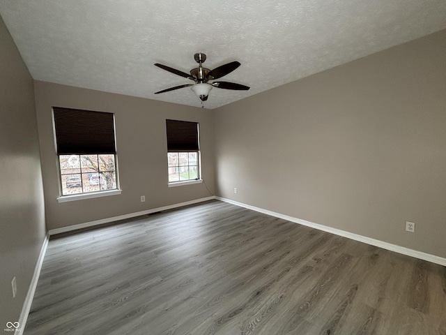 spare room with baseboards, wood finished floors, ceiling fan, and a textured ceiling