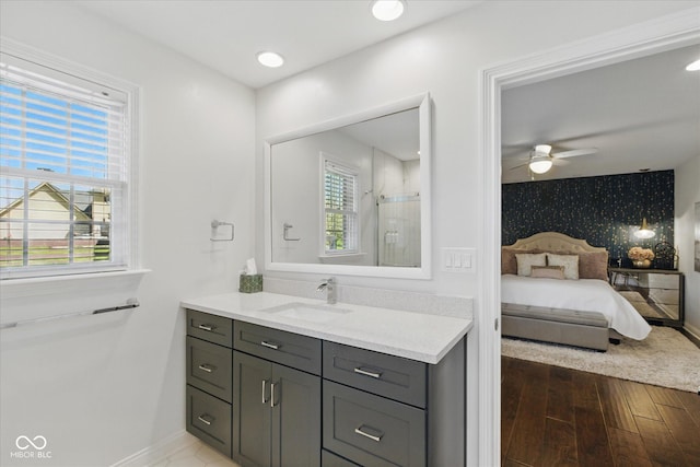 full bathroom featuring vanity, wood finished floors, baseboards, ceiling fan, and ensuite bath