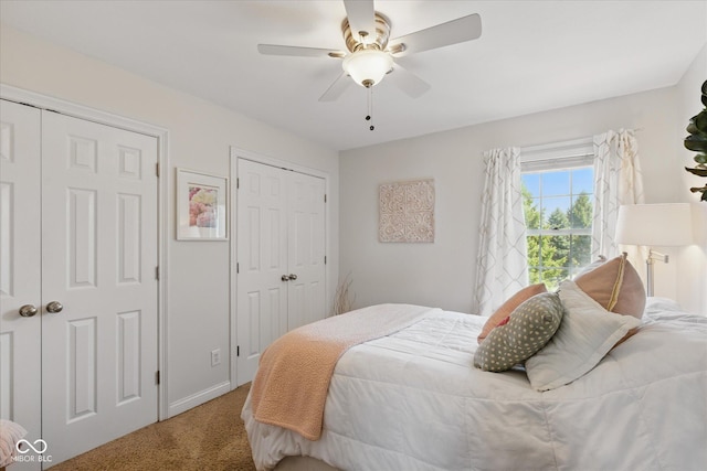 carpeted bedroom with a ceiling fan and multiple closets
