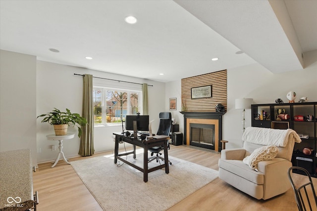 office space featuring a fireplace with flush hearth, recessed lighting, and light wood finished floors