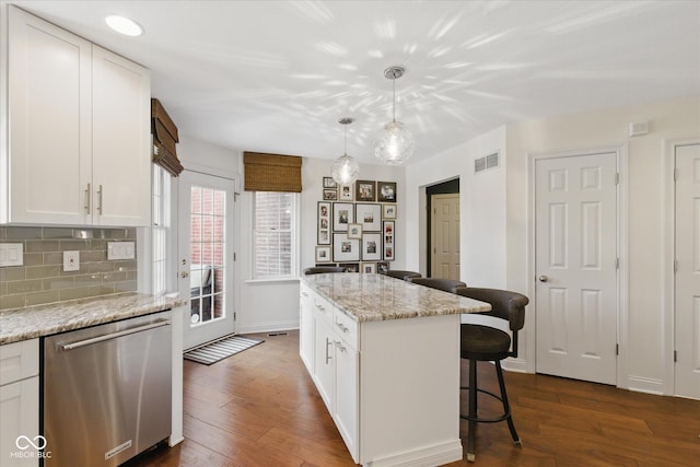 kitchen with visible vents, tasteful backsplash, dishwasher, a breakfast bar, and white cabinetry
