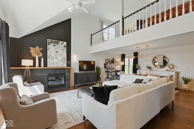 living room with wood finished floors, baseboards, ceiling fan, high vaulted ceiling, and a tiled fireplace