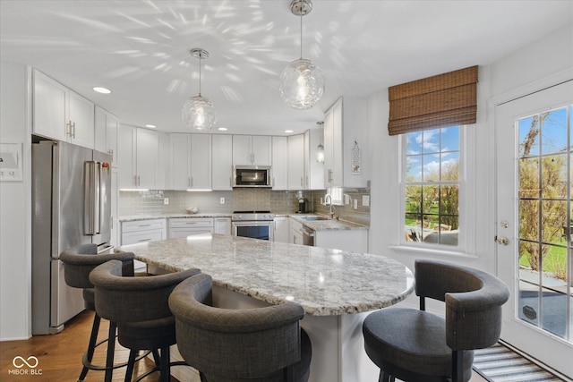 kitchen with a kitchen island, white cabinetry, appliances with stainless steel finishes, and a sink