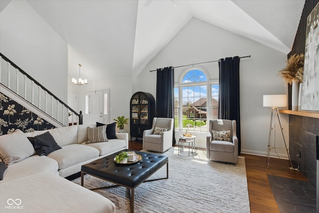 living room featuring wood finished floors, baseboards, high vaulted ceiling, stairway, and a chandelier
