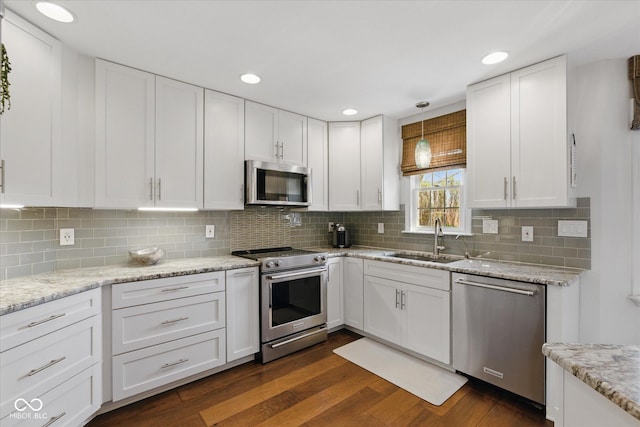 kitchen with a sink, decorative backsplash, stainless steel appliances, and white cabinetry