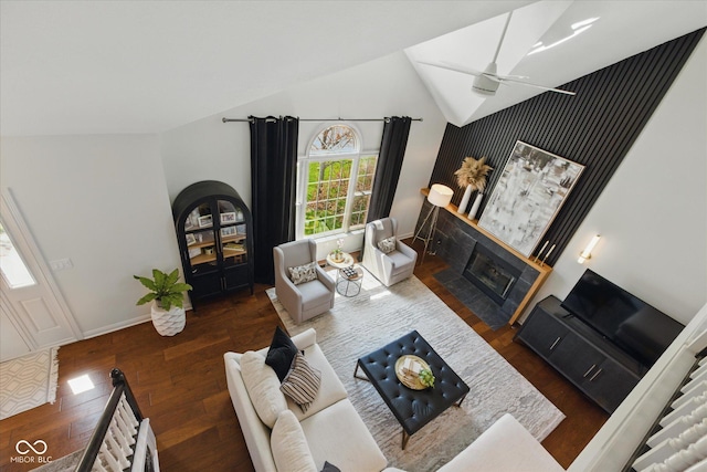 living room featuring wood finished floors, baseboards, ceiling fan, high vaulted ceiling, and a fireplace with flush hearth