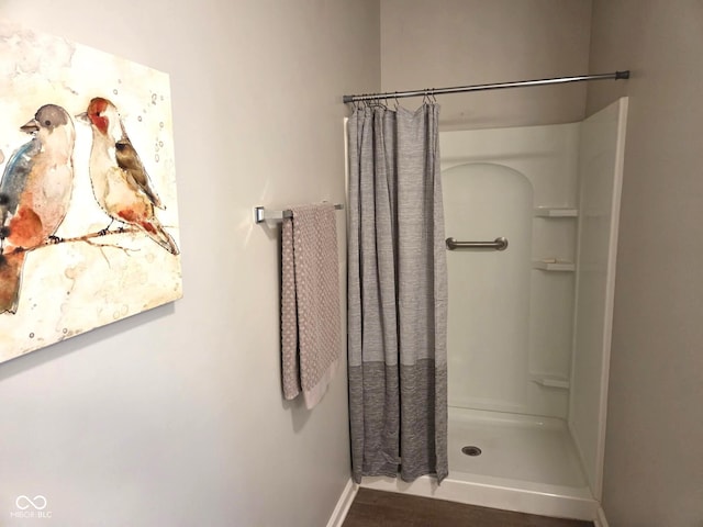 full bathroom with baseboards, wood finished floors, and a stall shower