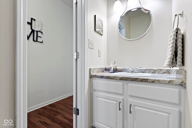 bathroom with wood finished floors, vanity, and baseboards