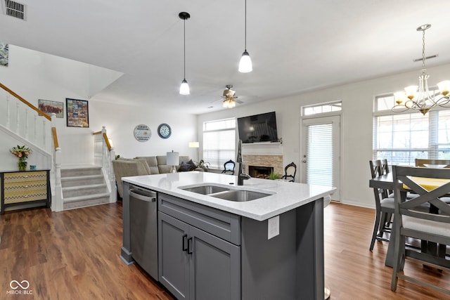 kitchen with stainless steel dishwasher, visible vents, gray cabinetry, a fireplace, and ceiling fan with notable chandelier
