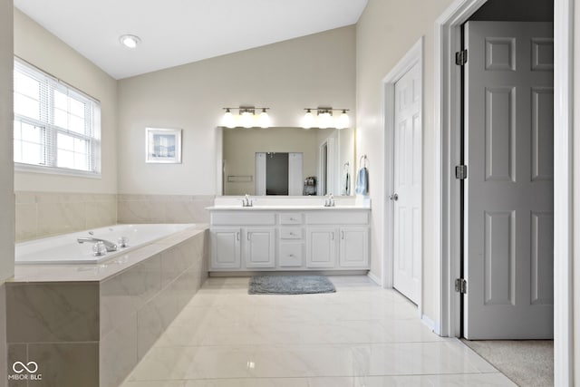 bathroom with a bath, double vanity, a sink, and vaulted ceiling