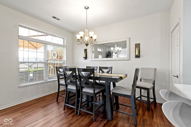 dining area with visible vents, wood finished floors, a chandelier, and baseboards