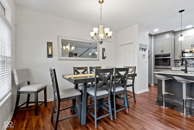 dining room featuring dark wood-type flooring, a chandelier, and baseboards