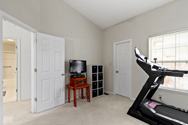 workout area featuring high vaulted ceiling, light colored carpet, and baseboards