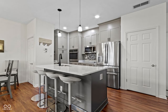 kitchen with dark wood-style floors, visible vents, stainless steel appliances, and a sink