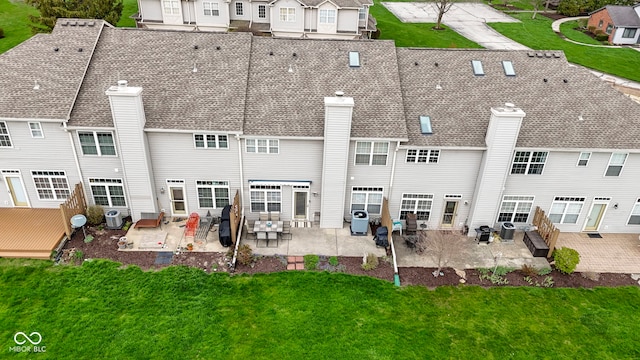 back of property with a lawn, a chimney, and a patio