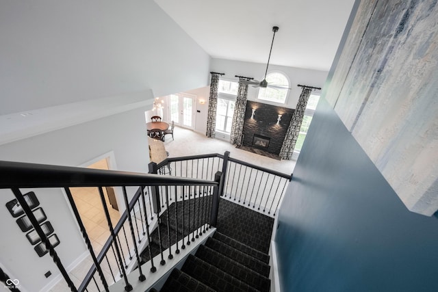 stairway featuring carpet floors and a stone fireplace