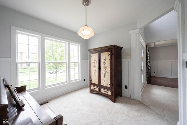 interior space featuring ornate columns, light colored carpet, wainscoting, and a decorative wall