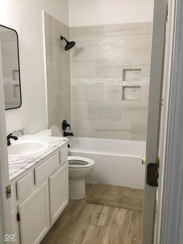 bathroom featuring toilet, wood finished floors, vanity, and bathing tub / shower combination