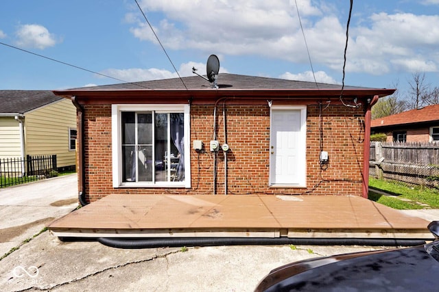 rear view of property featuring brick siding, fence, and a wooden deck