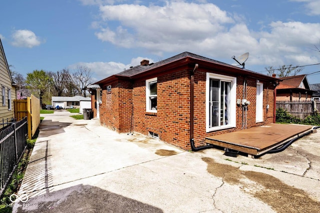 exterior space featuring a patio, driveway, fence, and brick siding