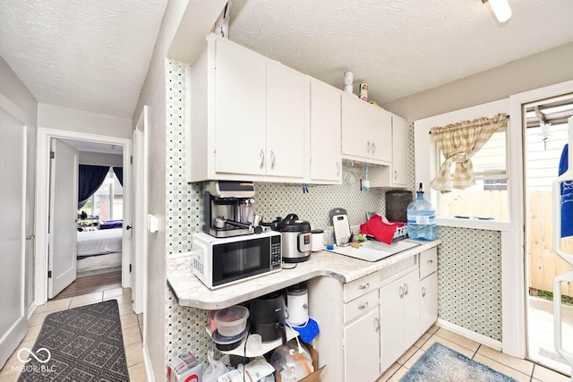 kitchen featuring light tile patterned floors, light countertops, a textured ceiling, and white cabinetry