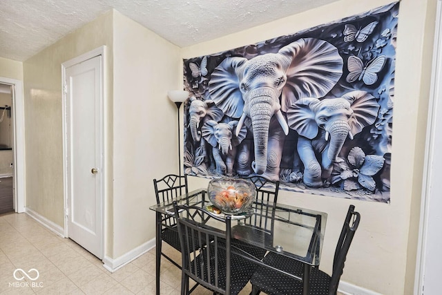dining room featuring tile patterned flooring, a textured ceiling, and baseboards