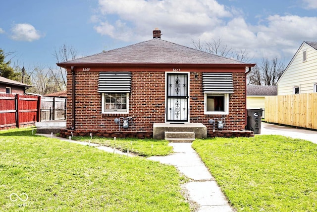 bungalow with a shingled roof, a front yard, fence, and brick siding