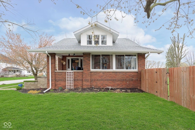 bungalow-style home featuring a front yard, a porch, fence, and brick siding